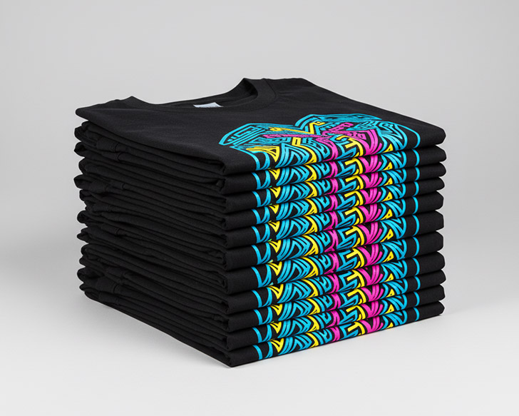 Una pila perfectamente ordenada de camisetas negras con diseños DTF idénticos y vibrantes en colores CMYK, mostrando uniformidad y calidad de impresión